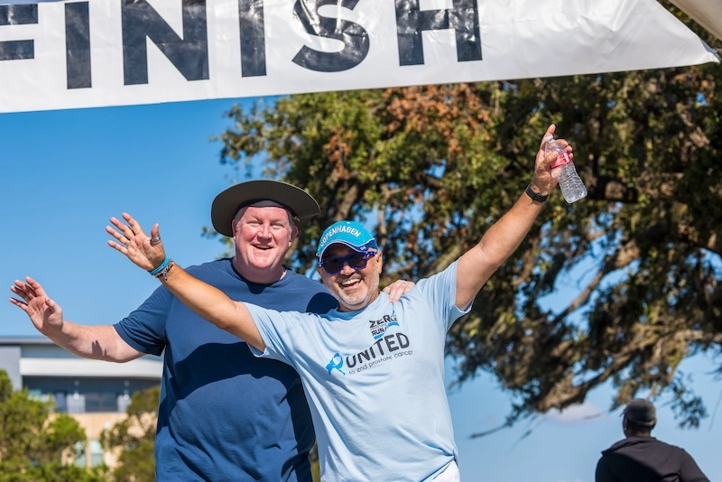 Two White male race participants celebrate at the finish line. Two White male race participants celebrate at the finish line.