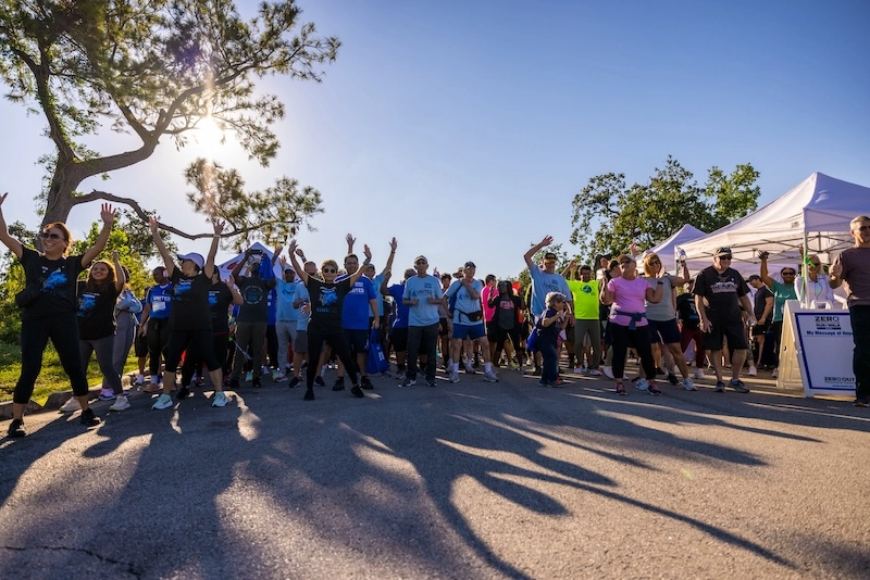 A group of dozens of race participants warm up with jumping jacks before the race.