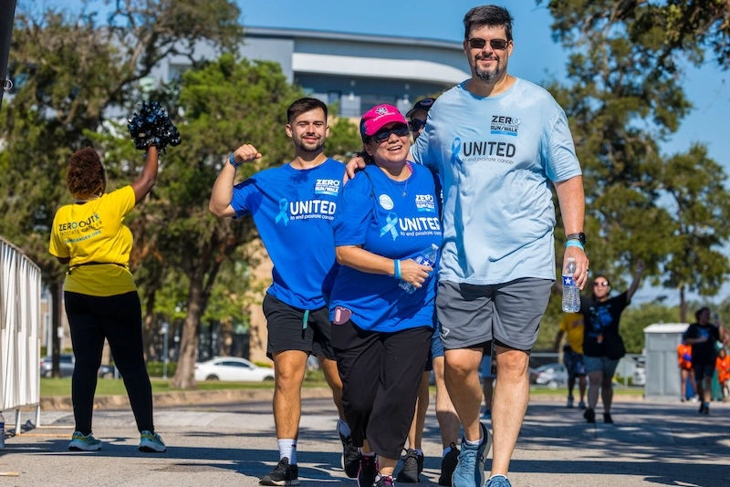 Three race participants smile at the camera during the race, with other participants in the background. Three race participants smile at the camera during the race, with other participants in the background.