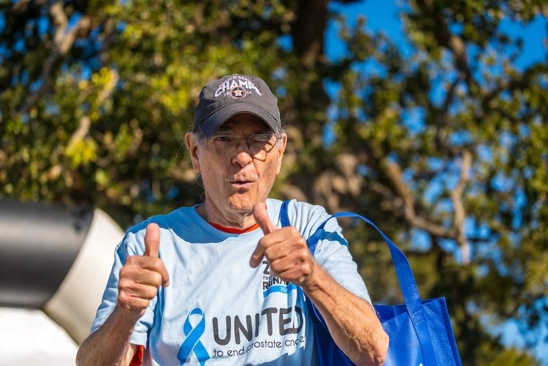 A While male older-aged race participant gives two thumbs up to the camera.
